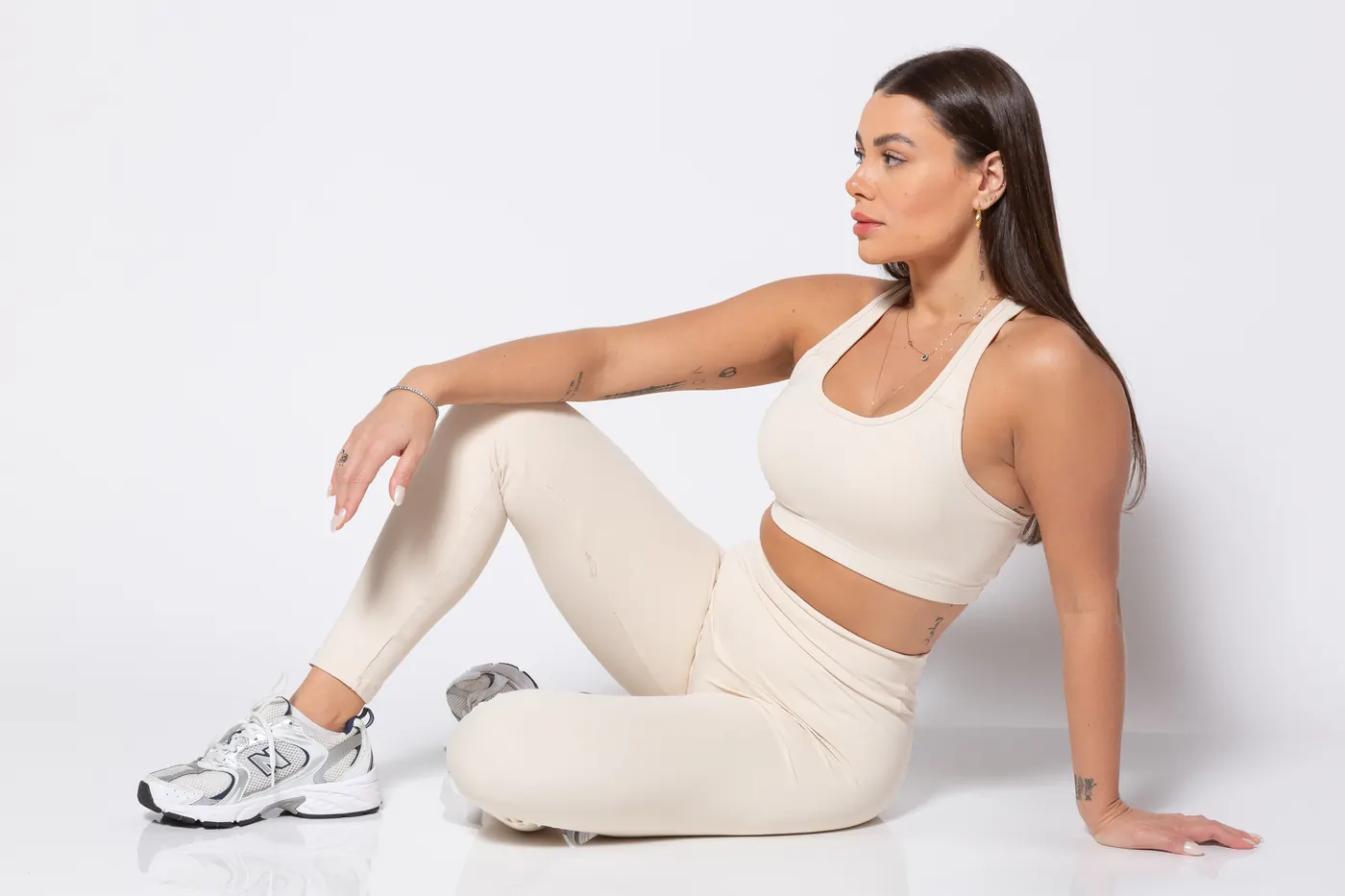 Mulher sentada no estúdio com conjunto off-white
